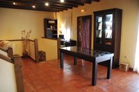 Salón de la casa rural La Fuente Gorda, con la escalera de bajada al garaje, zona de trabajo y puerta de acceso a la piscina.