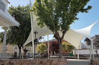 Plaza de Navas de Estena. Ayuntamiento, carpa (arquitectura textil) y escultura del ciervo debajo al fondo. Plaza de Navas de Estena. Ayuntamiento, carpa (arquitectura textil) y escultura del ciervo debajo al fondo.